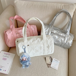 Detailed view of quilted bow cylinder bags in pink, beige, and silver on a soft sofa