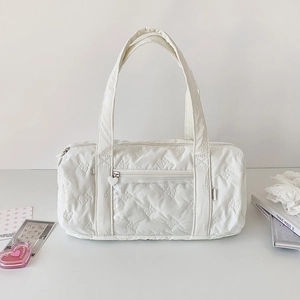 Detail of white quilted barrel bag featuring bow patterns and heart zipper pocket