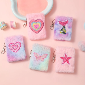 Close-up of plush mini notebook keychains with colorful embroidered patches and metal hooks