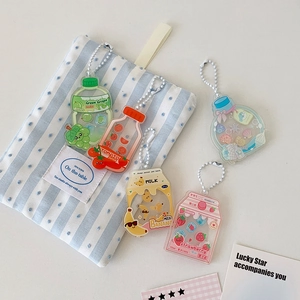 Detailed flat lay of five colorful acrylic soda bottle keychains with white bead chains