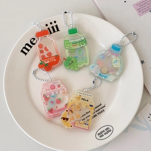 Detailed view of acrylic fruit juice liquid glitter keychains in a white ceramic plate