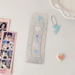 Close-up of clear glitter PVC photocard holder with dolphin charm and star patterns