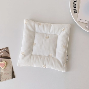 Gros plan d'un dessous de verre matelassé crème avec motifs de cœurs brodés