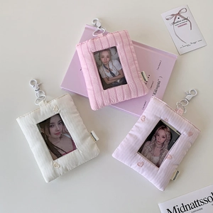 Detail of fabric card holders with transparent windows and metal hooks in soft colors