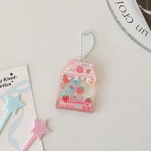 Détail d'un porte-clés shaker en acrylique lait fraise rose avec des breloques mobiles