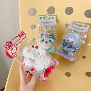 Three plush doll keychains in transparent boxes on a yellow chair, front display view