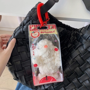 White plush animal keychain in apple themed packaging hanging on black woven bag