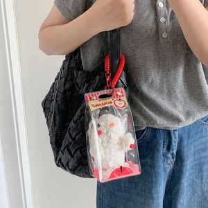 Detail view of transparent PVC doll display bag with white plush rabbit on a black bag