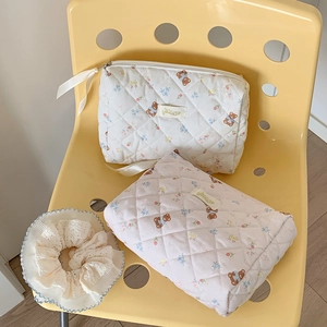 Detailed set of quilted bear cosmetic bags and a lace scrunchie on a yellow chair