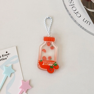 Détail d'un porte-clés acrylique jus de tomate avec chaîne à billes sur un bureau