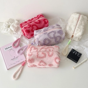 Detail of four colorful plush bags with heart patterns and woven zipper pulls