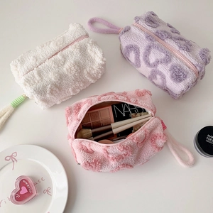 Plush heart-textured cosmetic pouches in white, purple and pink with zipper closure