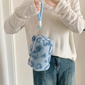Blue plush cylindrical makeup bag with polka dot texture and soft handle strap