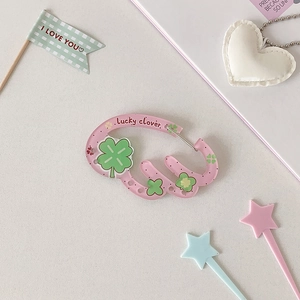 Macro detail of pink acrylic D-ring keychain featuring green lucky clover print