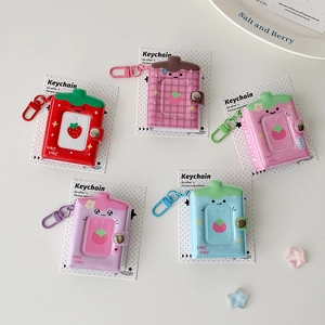 Mini strawberry-themed keychain photo albums in diverse pastel colors with metal snaps