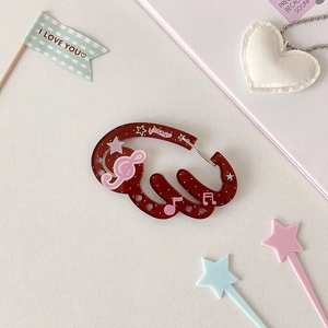 Detail of translucent dark red wing-shaped carabiner with pink musical notes and stars