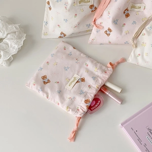 Detail of cartoon bear drawstring storage bag in soft cotton fabric with woven ropes