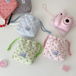 Close-up of quilted drawstring bags with cherry prints and woven cotton ropes