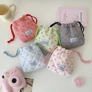 Flat lay of colorful quilted cherry plaid drawstring bags with aesthetic lifestyle props