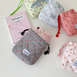 Flat lay of quilted cherry plaid drawstring storage bags in five vibrant colors