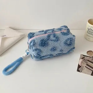Dettaglio della borsa trucco in peluche celeste con motivi a cuore e zip rosa accesa