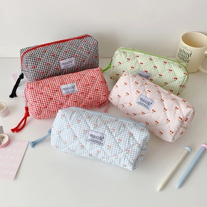 Quilted cherry plaid pencil cases in five colors arranged on a white desktop