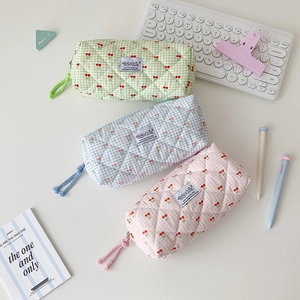 Three quilted cherry plaid pencil cases with woven zipper pulls on a white desk
