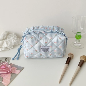 Detailed view of blue checkered quilted pencil case with cherry print and ruffle trim