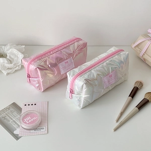 Detail of star-quilted pearlescent pouches with ribbon labels and aesthetic stitching