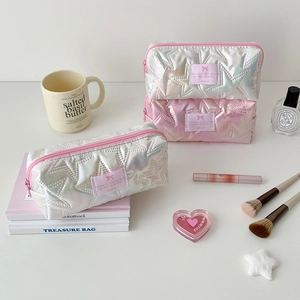 Detailed view of iridescent star-quilted pencil cases and cosmetic bags on white desk