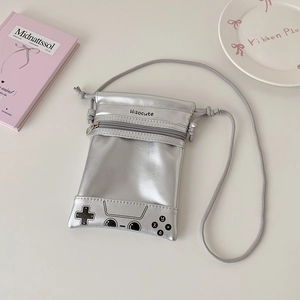 Detail of silver crossbody bag shaped like a retro game controller with soft pink decor