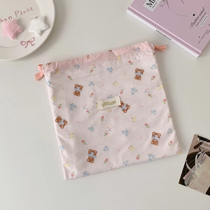 Pink drawstring storage bag with cute bear and rabbit prints on a creamy desk