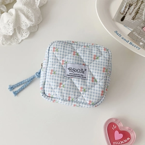 Detailed view of a blue checkered quilted mini pouch with red cherry pattern and zipper