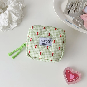 Macro detail of quilted cherry print makeup pouch with checkered fabric and green zipper