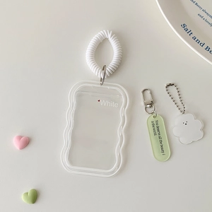 Close-up of clear wavy edge photocard holder with spring lanyard and cloud charm