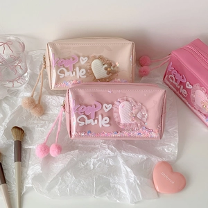Detail of pink and beige pouches with heart sequins, glitter and fluffy pompom charms