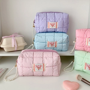 Detail of quilted macaron colored pencil cases with pearl handles and heart embroidery