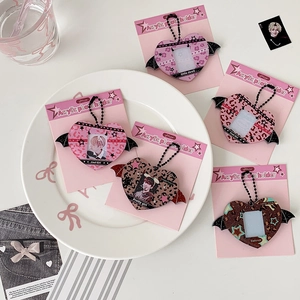 Flat lay of heart-shaped acrylic photocard holders with bat wing designs and bead chains