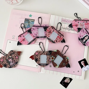 Macro detail of heart-shaped acrylic card holder with wings and leopard print patterns