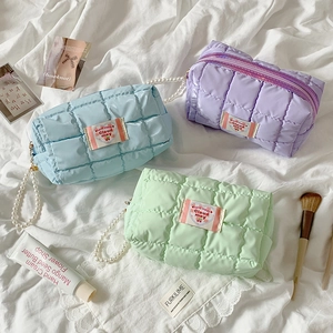 Detailed macro view of quilted pastel pouches with pearl handles and heart shaped labels