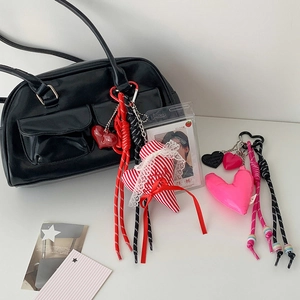 Detail of red striped fabric heart charm with lace and braided rope on a leather bag