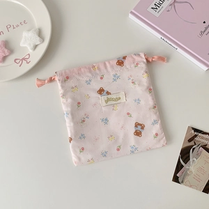 Close-up of pink drawstring bag with cute bear and bunny patterns on a soft desk setting