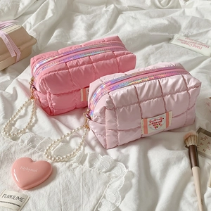 Detailed shot of quilted pink makeup bag with pearl handle and heart-shaped logo tag