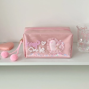 Detailed view of pink pencil case featuring quicksand sequins and plush pompom zippers