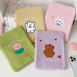 Detail of colorful corduroy iPad sleeves featuring cartoon bear and floral embroidery