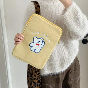Close-up of yellow corduroy laptop sleeve featuring a happy day bear embroidery