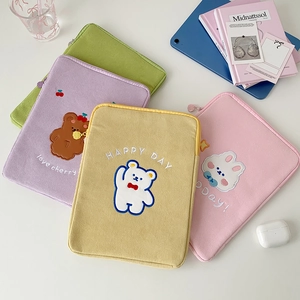 Detail of embroidered corduroy iPad sleeves in pastel green, purple, yellow, and pink colors