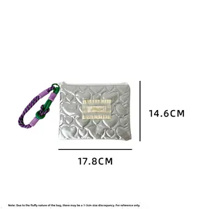 Détail d'une trousse à maquillage argentée matelassée avec des motifs de cœurs