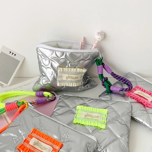 Détail de la trousse à maquillage argentée matelassée avec cordon de transport