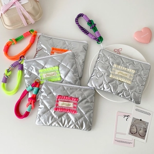 Détail de pochettes maquillage argentées matelassées avec anses en corde tressée colorée